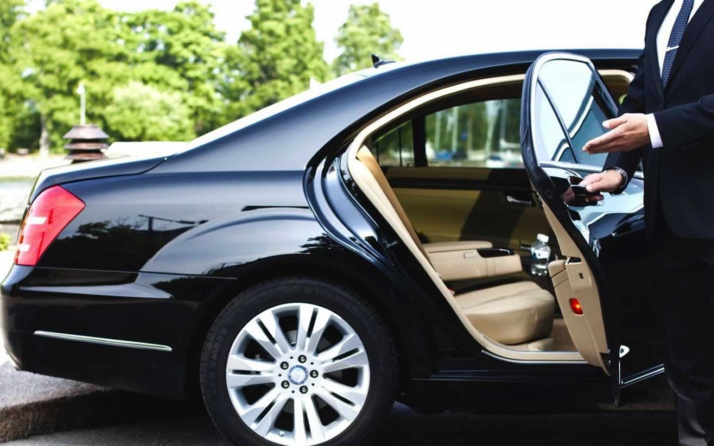 Chauffeur holds open the door of a limousine
